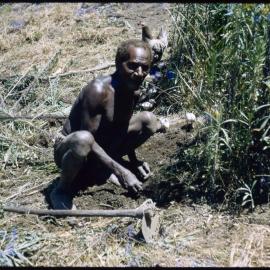 Man Crouching Beside Plants