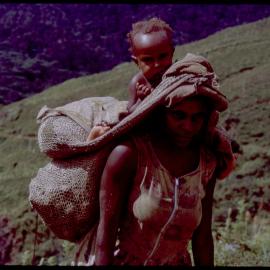 Woman Carrying Net Bags and a Child