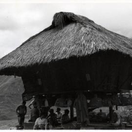 Group Sitting Beneath Wooden Structure on Stilts