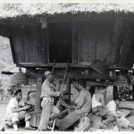 Group Sitting Beneath Wooden Structure on Stilts