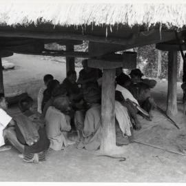 Group Sitting Beneath Wooden Structure on Stilts