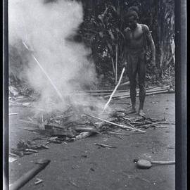 [Manum Island, New Guinea] Two Men Cooking Bananas etc in the Ashes of a Fire with which to Refresh the Workers