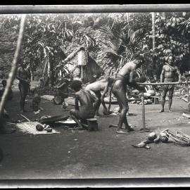 [Manum Island, New Guinea] Making the 'Bed'. Fixing the Transverse Posts. Other Men Scraping Coconuts or Just Sitting Looking On
