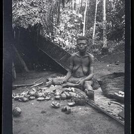 [Manum Island, New Guinea] A Woman Cutting Open i Nuts